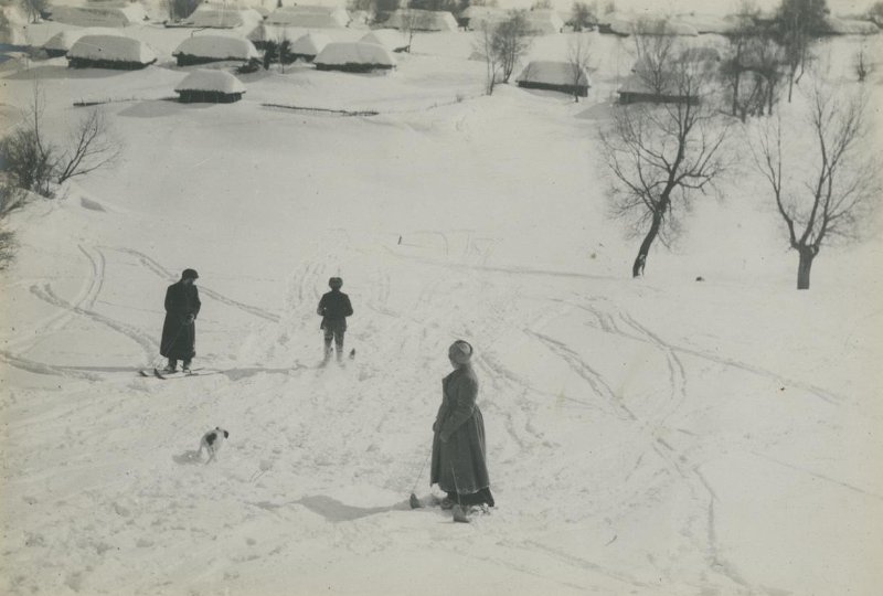 А.Л. Толстая, Н.Н. Гусев и В.В. Чертков катаются на лыжах со склона около деревни