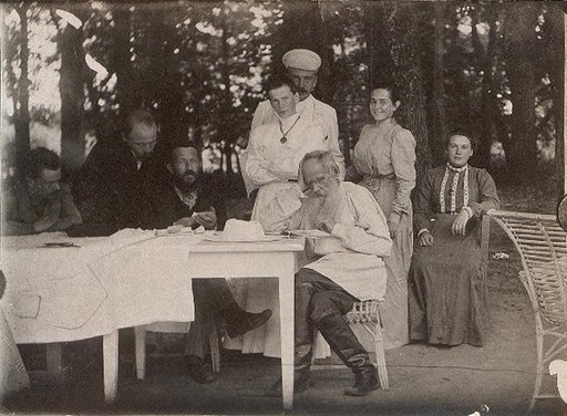 Л.Н. Толстой в белой блузе с книгой за столом