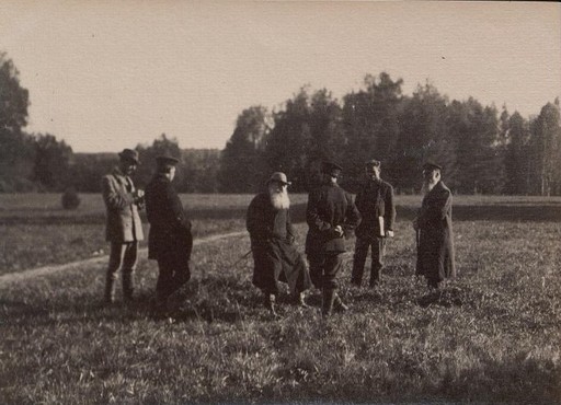 Л.Н. Толстой в пальто и шляпе сидит на лугу